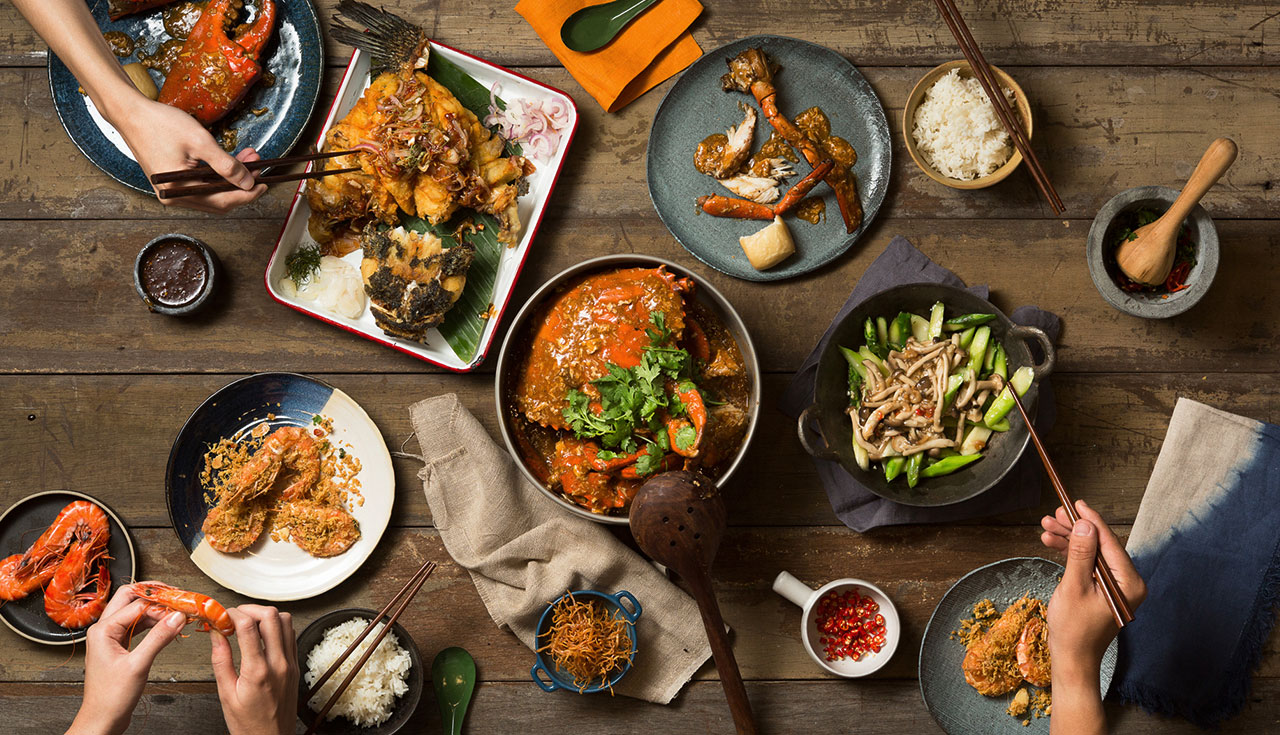 A shared table of chilli crab, prawns, fish, rice, and vegetables at Palm Beach Seafood